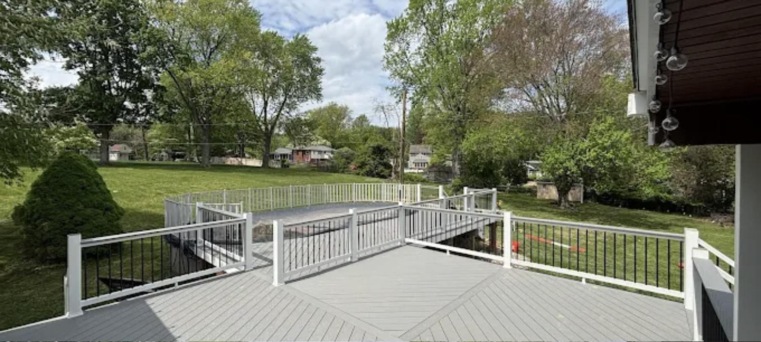 Custom deck build with large composite deck and white railing overlooking backyard
