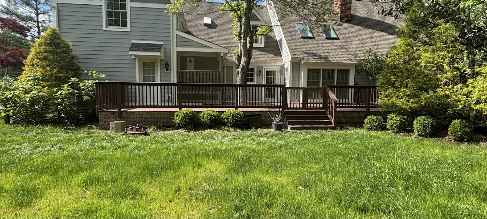 Custom deck build in wood with railing and stairs surrounded by green lawn, RC Deck Co project
